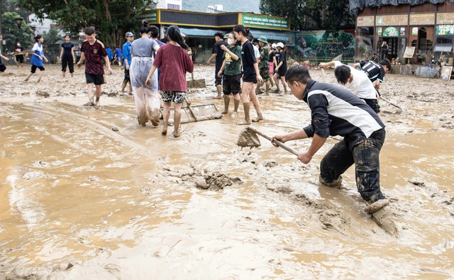 Người dân vất vả dọn dẹp đường phố sau trận ngập lụt vì mưa bão